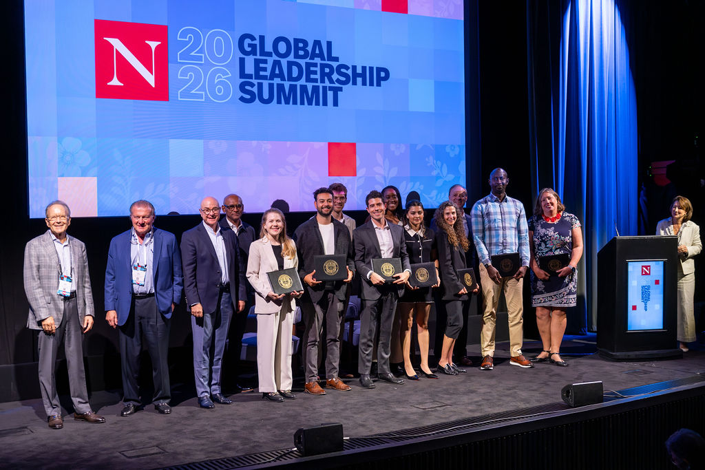 A group of people on stage at the 2026 Global Leadership Summit; some hold awards and pose for a photo in front of a large screen displaying the event name and logo.